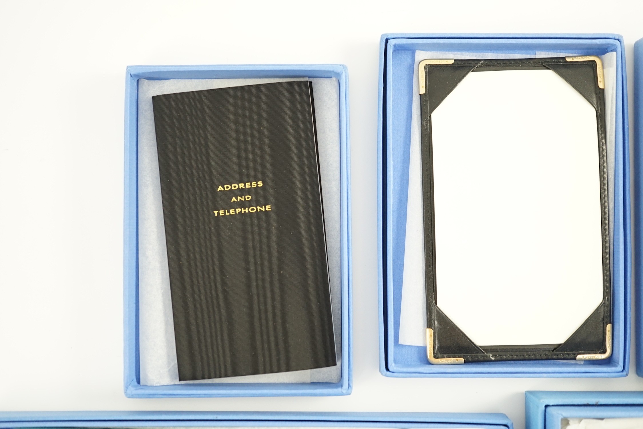 Smythson of London. A black leather notepad, 14cm, two moire silk address/telephone books, a pale grey leather purse,18cm, a Panama cornflower blue notebook, 14 cm and a duck egg blue purse, 20 cm. all boxed.
